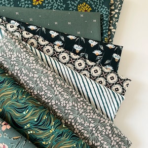May include: A stack of ten fabric squares in various shades of green with different floral and geometric patterns. The fabric is soft and has a subtle sheen.