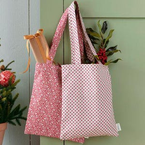 May include: Two reusable tote bags with red and white patterns. One bag has a red and white polka dot pattern, and the other has a red and white floral pattern.