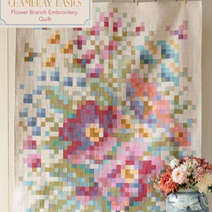 May include: A large, rectangular quilt with a floral design. The quilt features a pixelated pattern of flowers in shades of pink, purple, blue, and yellow against a neutral background. The text "CHAMBRAY BASICS Flower Branch Embroidery Quilt" is visible.