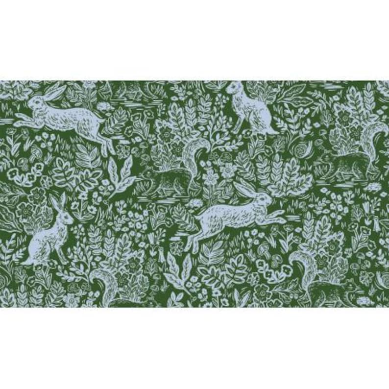 Puede incluir: Una tela verde con un patr&oacute;n repetido de conejos blancos y ardillas corriendo por un bosque de hojas y flores.