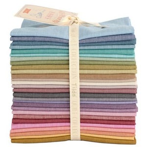 Puede incluir: Una pila de 20 cuadrados de tela en varios tonos de azul, verde, marrón, beige, gris, morado, rosa, naranja y amarillo. La tela es un material suave, similar al lino. Los cuadrados de tela están atados con una cinta blanca.
