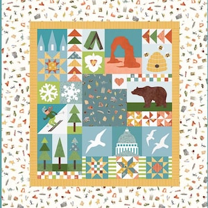 May include: A colorful patchwork quilt featuring various nature and architectural designs. The quilt showcases images of a bear, a beehive, a skier, and a capitol building. The border is a mix of white, yellow, and teal.