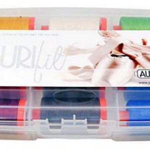 Może przedstawiać: Przezroczysty plastikowy pojemnik wypełniony szpulami kolorowej nici. Pojemnik ma etykietę z napisem "Aurifil Classic Collection".
