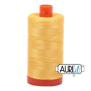 May include: A spool of yellow thread with a red plastic top and bottom. The thread is labeled "Aurifil" in blue text.