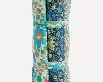 Op de afbeelding: Een bundel stoffen rollen met bloempatronen, vastgebonden met een lint. De stoffen tonen bloemmotieven in tinten blauw, groen en wit. De rollen zijn netjes gerangschikt, geschikt voor knutsel- en naaiprojecten.