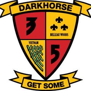 Puede incluir: Un escudo amarillo y rojo con un número negro "5" y un diseño de bambú verde. El escudo está rodeado por una pancarta amarilla con el texto "DARKHORSE" y "GET SOME".