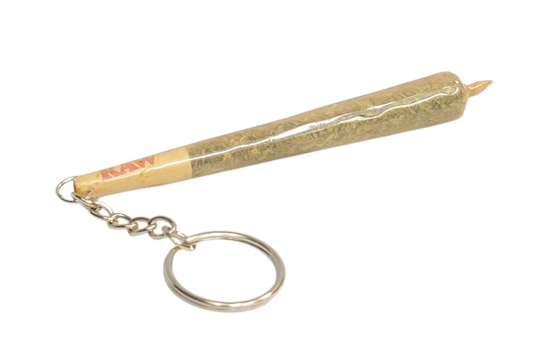May include: A silver keychain with a realistic-looking joint, wrapped in a brown paper with the word "RAW" printed on it.