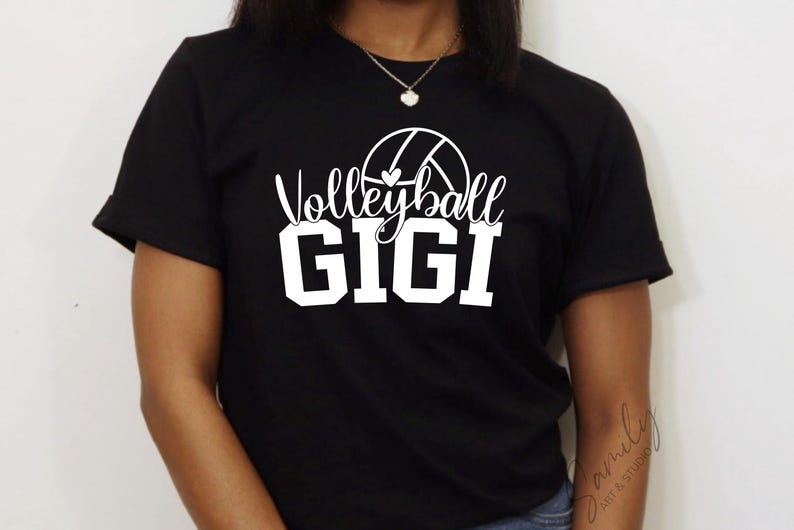 May include: Black t-shirt featuring the text "Volleyball GIGI" in white, with a volleyball graphic. The shirt has short sleeves and is likely made of cotton. The text is in a mix of script and block letters.