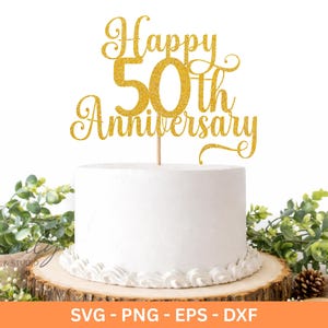 May include: A white cake with a gold glitter "Happy 50th Anniversary" cake topper. The cake sits on a wooden base, decorated with greenery and a pinecone. The cake topper is on a wooden stick.