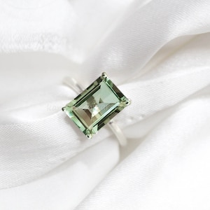 Op de afbeelding: Een zilveren ring met een grote, smaragd geslepen groene edelsteen.