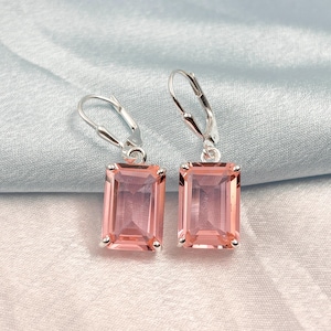 Könnte beinhalten: Ein Paar silberne Ohrhänger mit rechteckigen rosa Edelsteinen. Die Ohrringe haben einen Bügelverschluss.
