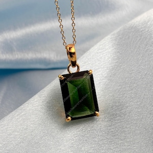 Puede incluir: Un collar de cadena de oro con un colgante que presenta una piedra rectangular verde oscura grande.
