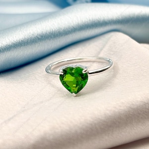 May include: A silver ring with a heart-shaped green gemstone.