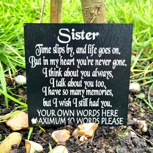 May include: A black slate memorial plaque with white text. The plaque is inscribed with a poem dedicated to a sister, with space for custom text at the bottom. The plaque is placed in a garden setting.