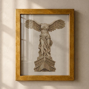 May include: A framed cross-stitch embroidery depicting the Winged Victory of Samothrace statue in shades of beige and brown. The artwork is encased in a textured, metallic gold-toned frame with a rectangular profile and a clear glass front.