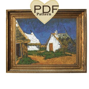 May include: A framed cross-stitch pattern of a painting depicting two white houses with thatched roofs against a blue sky. The houses are set in a field with green grass and a dirt path leading between them.