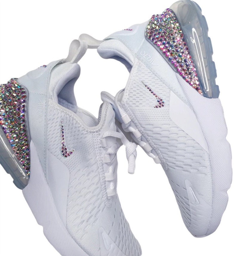 Pode incluir: T&ecirc;nis Nike Air Max 270 brancos com cabedal de malha branca e sola de bolha de ar transparente. Os t&ecirc;nis s&atilde;o decorados com strass iridescentes no calcanhar e no swoosh.