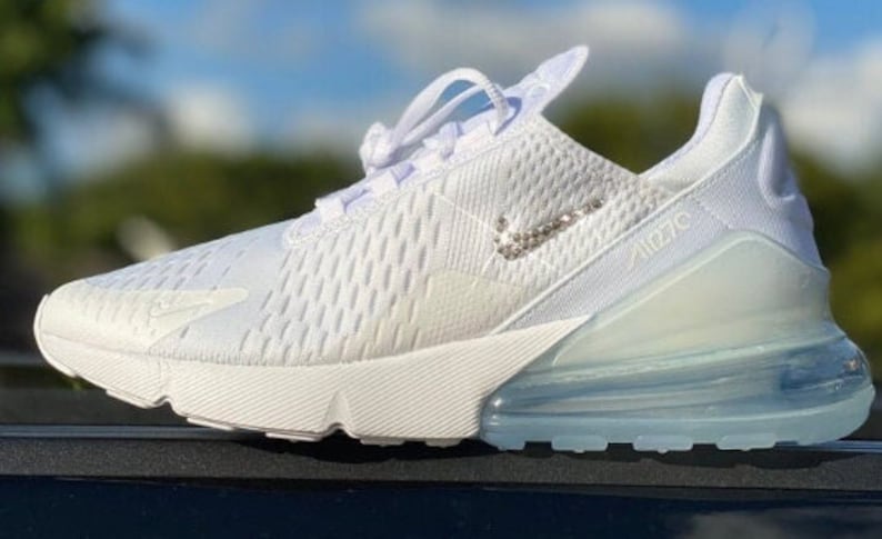 May include: White Nike Air Max 270 trainers with a white mesh upper and a clear air bubble sole. The Nike swoosh is made of rhinestones.
