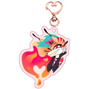 Puede incluir: Un llavero de acr&iacute;lico en forma de coraz&oacute;n rosa, naranja y amarillo con una imagen de dibujos animados de un zorro pelirrojo de ojos azules con una sonrisa traviesa. El zorro lleva un atuendo blanco y negro con un coraz&oacute;n rojo en el pecho. El llavero tiene un cierre de metal en forma de coraz&oacute;n dorado.