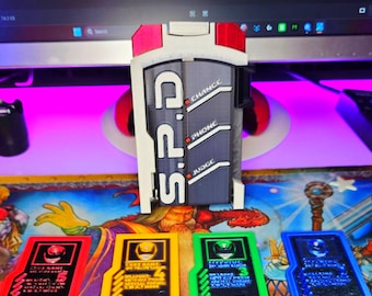 May include: A 3D-printed prop resembling a futuristic police badge, with the text "S.P.D." and "CHANGE", "PHONE", and "JUDGE" labels. Four colored cards are below, each with a number and the word "POLICE". The background includes the text "HEROIC STUDIOS".