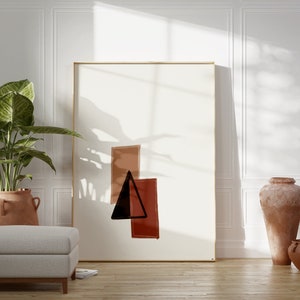 May include: A white room with a large framed abstract painting featuring a black triangle and red and brown rectangles. A potted plant with green leaves is in the corner of the room. Two terracotta pots are on the floor.