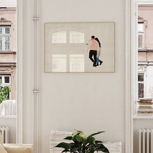 May include: A framed illustration of a couple standing in front of a window. The man is wearing a striped shirt and the woman is wearing a blue shirt. The illustration is in a light brown frame and is hanging on a white wall.