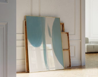 May include: A framed abstract painting with a blue and white color scheme. The painting is leaning against a white wall.