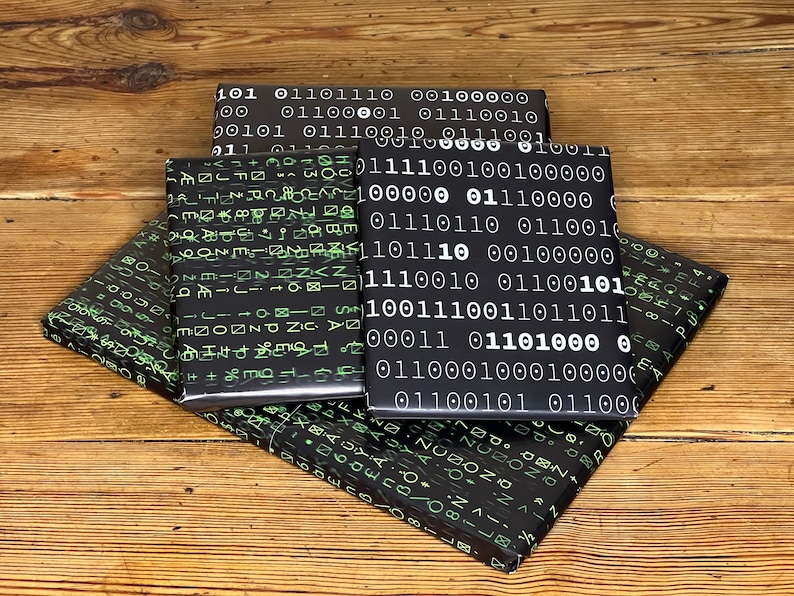 以下が含まれることがあります： 白と緑のバイナリコードパターンが施された黒いギフト包装紙4枚。紙は互いに重ねられています。