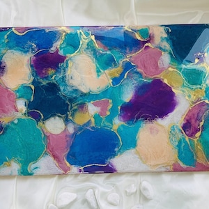 Puede incluir: Obra de arte abstracta rectangular con acabado brillante. La obra presenta una vibrante mezcla de colores, incluyendo turquesa, azul, morado, rosa y dorado. El dise&ntilde;o incorpora formas org&aacute;nicas y patrones fluidos.