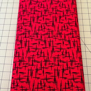 May include: Red fabric with a black and white geometric pattern. The pattern is made up of thin lines that create a grid-like effect.