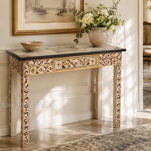 May include: A rectangular console table featuring intricate floral and geometric inlay patterns in shades of brown, orange, and cream. The table has a single central drawer with a clear knob, four straight legs, and a dark-edged top surface.