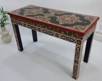 May include: A black and red console table with intricate floral designs painted on the top and sides. The table has four legs and a rectangular top.