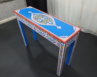 May include: A blue console table with intricate hand-painted floral designs in red, yellow, and white. The table has a rectangular top and two legs.