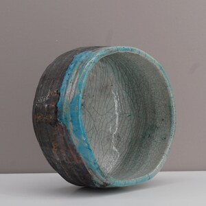 Puede incluir: Un cuenco de cer&aacute;mica con un esmalte craquelado en tonos de blanco y azul. El cuenco tiene un borde marr&oacute;n oscuro y una banda turquesa alrededor del borde.