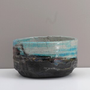 Puede incluir: Un cuenco de cer&aacute;mica con un esmalte azul y blanco. El cuenco tiene un exterior rugoso y texturizado y un interior liso y brillante.