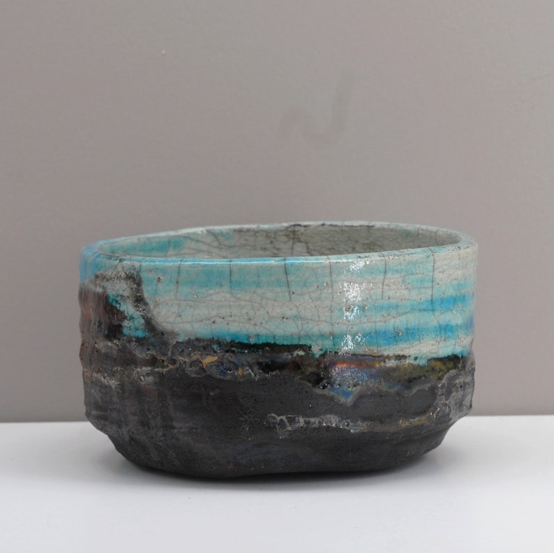 Puede incluir: Un cuenco de cer&aacute;mica con un esmalte azul y blanco. El cuenco tiene un exterior rugoso y texturizado y un interior liso y brillante.