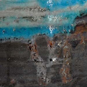 Puede incluir: Primer plano de una superficie de cer&aacute;mica con un esmalte azul y blanco. La superficie tiene una textura rugosa y est&aacute; cubierta de peque&ntilde;as manchas marrones.