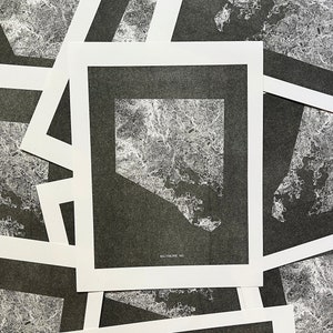 May include: A stack of black and white prints of the Baltimore, MD city map. Each print is framed with a white border and has the text "Baltimore, MD" at the bottom.