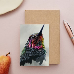 May include: A close-up of a hummingbird with iridescent green, blue, and pink feathers. The bird's head is tilted up, and its eye is visible.