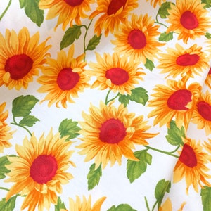Peut inclure: Tissu blanc avec un motif répétitif de tournesols jaunes avec des centres rouges. Les tournesols sont disposés en quinconce et ont des feuilles vertes.