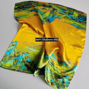 K&ouml;nnte beinhalten: Ein gelber Seidenschal mit einem Landschaftsdesign mit gr&uuml;nen und blauen Bergen und einem Fluss. Der Schal tr&auml;gt den Aufdruck "100% Maulbeersilk".