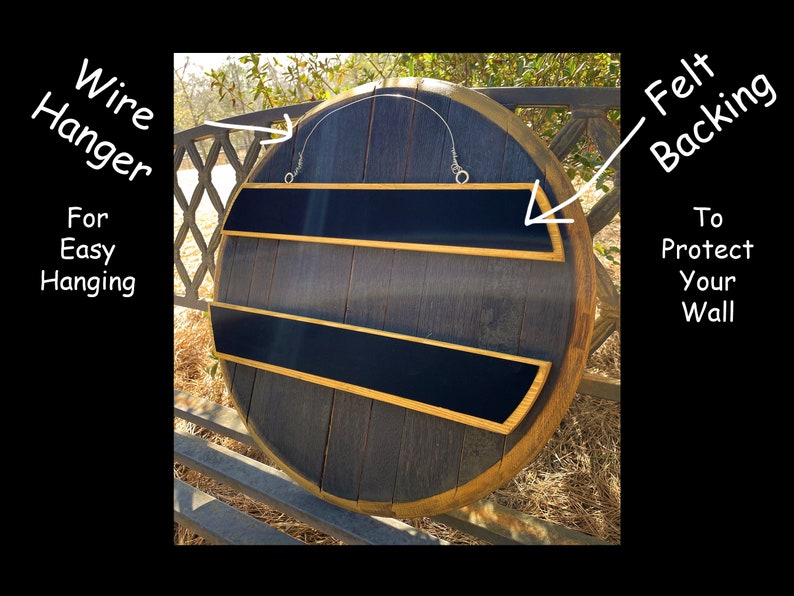 May include: A round, dark wood wall shelf with two black shelves and gold trim. The shelf has a wire hanger for easy hanging and felt backing to protect the wall. The wood has a natural grain, and the overall design is rustic.