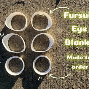 May include: Six white, oval-shaped fursuit eye blanks are arranged on a textured, brown surface. The text "Fursuit Eye Blanks Made to order" is written in green. These blanks are designed for creating custom fursuit eyes.