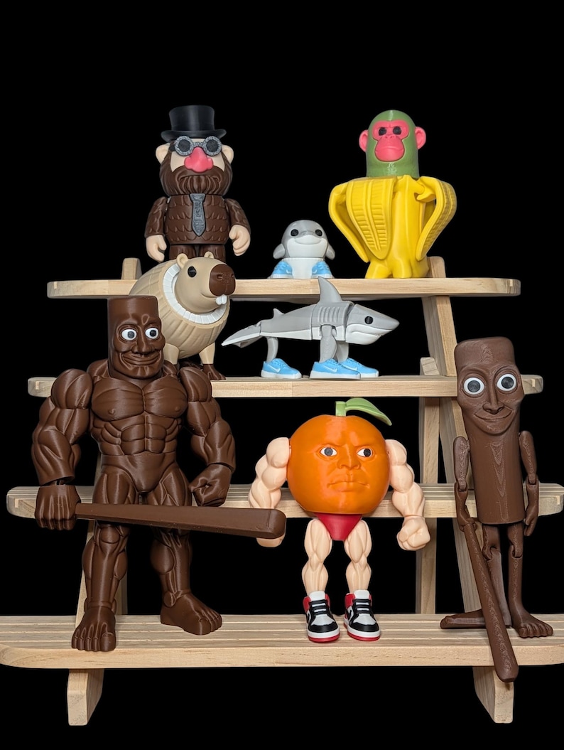 Puede incluir: Una colecci&oacute;n de figuras caprichosas exhibidas en una estanter&iacute;a de madera. Las figuras incluyen un tibur&oacute;n, un mono en un pl&aacute;tano, un carpincho, un hombre con traje, un delf&iacute;n, una figura musculosa con un bate, una naranja con brazos y piernas y una figura de madera.