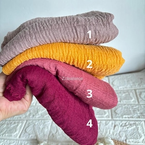May include: Four pieces of crinkle cotton fabric in different colours: mauve, yellow, pink, and burgundy.