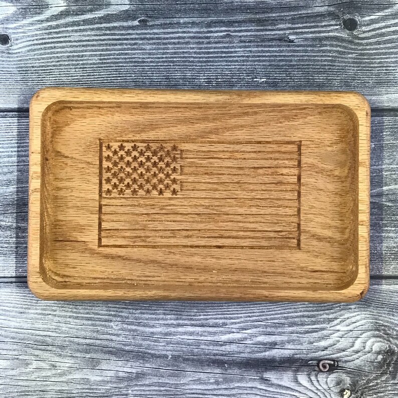 May include: A wooden tray with a carved American flag design. The tray is made of light brown wood and has a rectangular shape.