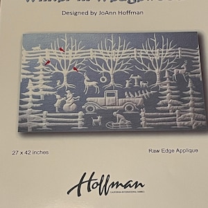 May include: A winter scene with a blue background and white snow-covered trees. A red truck with a white roof is driving through the snow. The scene is framed by a white picket fence. The text "Winter in Wedgewood" and "Designed by JoAnn Hoffman" is at the top of the image. The text "27 x 42 inches" and "Raw Edge Applique" is at the bottom of the image. The text "Hollman" is at the bottom center of the image.