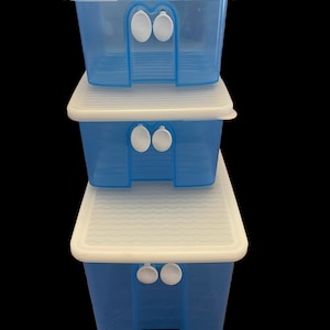 May include: Three stackable plastic storage containers with white lids. The containers are blue and have a wavy texture on the bottom. The lids have a grid pattern and two white tabs on the front.