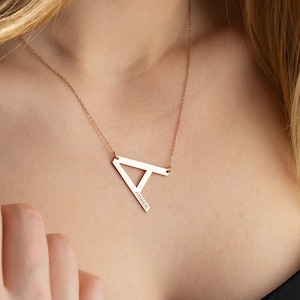 Puede incluir: Un collar de oro con un colgante de letra 'A' geométrica grande. El colgante tiene el nombre "Amber" grabado.