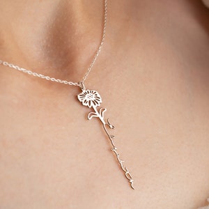 Könnte beinhalten: Eine silberne Halskette mit einem zarten Blumenanhänger und dem Wort "forever" auf dem Stiel.